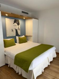1 dormitorio con 1 cama blanca grande con almohadas verdes en Arthur Properties Rue d'Antibes, en Cannes