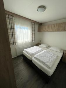 een slaapkamer met 2 bedden en een raam bij Chalet (A16) op gezellige familiecamping bij zee in Kamperland
