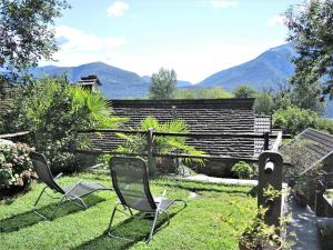 twee stoelen in een tuin met bergen op de achtergrond bij Rustico Gatto & Topolino in Agarone