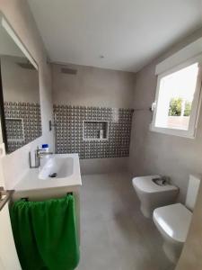 ein Bad mit einem Waschbecken, einem WC und einem Fenster in der Unterkunft Casita moderna a escasos metros de Playa Terranova in Oliva