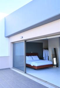 PaianíaにあるSpacious & Minimal Apartment Near Airport Peania Coniann Filoxeniaのベッドルーム1室(ベッド1台付)、スライド式ガラスドアが備わります。