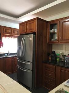 a kitchen with a stainless steel refrigerator and wooden cabinets at Comfortable home in San Fernando in San Fernando