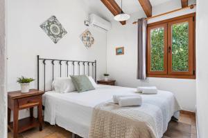 a white bedroom with two beds and a window at Sa Lluna in Binibeca