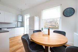 a kitchen with a wooden table and chairs and a clock at Trendy East London Flat BRO1 in London