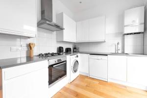 a white kitchen with a stove and a dishwasher at Trendy East London Flat BRO1 in London