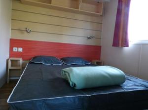 a large bed with a blue pillow on top of it at Camping maeva Escapades Les Etangs Mina in Saint-Sornin