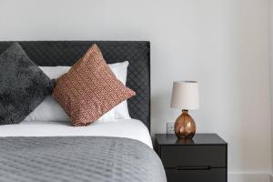 a bed with pillows and a table with a lamp at Trendy East London Flat BRO1 in London