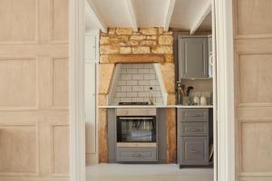 a kitchen with gray cabinets and a stone wall at Boutique Chic In Blockley in Blockley