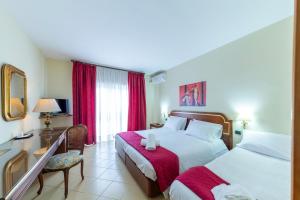 a hotel room with two beds and a table and chair at Hotel Sakura in Torre del Greco