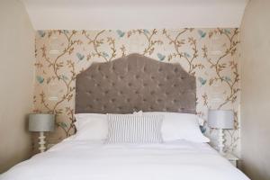 a bedroom with a white bed with a large headboard at Boutique Chic In Blockley in Blockley