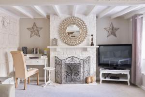 a living room with a fireplace and a mirror at Boutique Chic In Blockley in Blockley