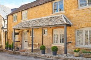 ein Backsteingebäude mit einer Veranda mit einer Bank in der Unterkunft Boutique Chic In Blockley in Blockley