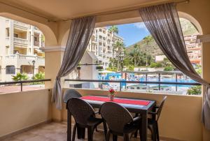 balkon ze stołem i krzesłami oraz widokiem na basen w obiekcie Castle Harbour Cozy Studio Heated Pool Los Cristianos LoveTenerife w Aronie