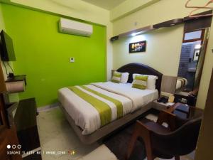 ein grünes Schlafzimmer mit einem Bett und einem Schreibtisch mit einem TV in der Unterkunft Hotel Prabhat in Varanasi