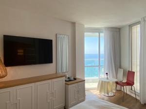 ein Wohnzimmer mit Flachbildfernseher und einem Tisch in der Unterkunft King Solomon Hotel in Netanya