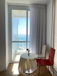 einen Tisch und Stühle in einem Zimmer mit einem großen Fenster in der Unterkunft King Solomon Hotel in Netanya