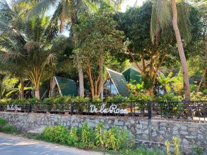 a resort with palm trees and a stone wall at Homestay De la Rosa - Côn Đảo in Con Dao