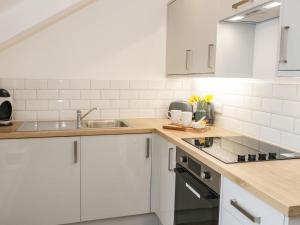 a kitchen with white cabinets and a sink at Tŷ Capel Bach in Bangor
