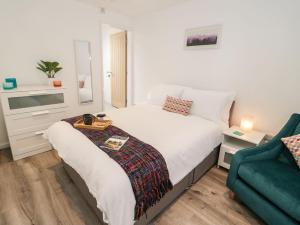 a bedroom with a white bed and a green couch at Tŷ Capel Bach in Bangor