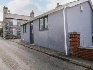 a gray house with a brick building on a street at Tŷ Capel Bach in Bangor