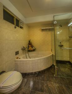 a bathroom with a tub and a toilet and a shower at Pai Viceroy in Bangalore