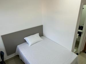Una cama blanca con una almohada encima. en NANO Suítes en Uberlândia