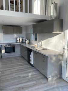 a large kitchen with stainless steel appliances and gray cabinets at La petite maison de Vence in Vence