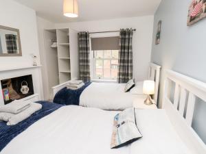 2 Betten in einem kleinen Zimmer mit Fenster in der Unterkunft Braeside in Whitby