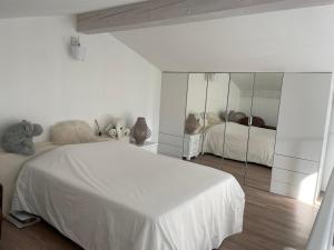 1 dormitorio blanco con 2 camas y un espejo grande en La petite maison de Vence, en Vence