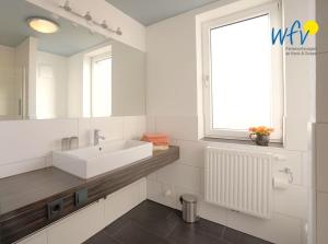 uma casa de banho branca com um lavatório e uma janela em Barons Residenz Borkum Ferienwohnung 7 em Borkum