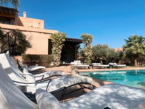 una piscina con sedie a sdraio accanto a un edificio di Villa Singulière By Louhou Collection a Marrakech