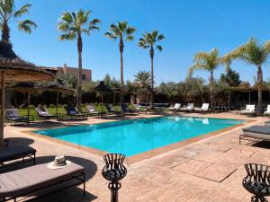 a swimming pool with chairs and palm trees at Villa Singulière By Louhou Collection in Marrakesh