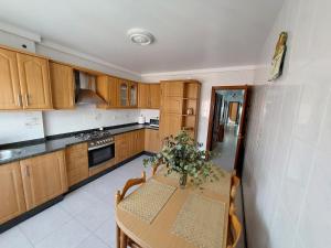 a kitchen with wooden cabinets and a table with flowers on it at Apartamento Buserán in Muxia