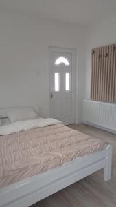 a white bedroom with a bed and a window at Apartman Milena Temerin in Temerin