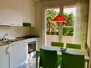 a kitchen with a table with green chairs and a window at Garni Villa Siesta Park in Losone