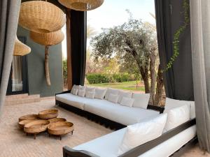 un soggiorno con divano e tavoli bianchi e una finestra di Villa Singulière By Louhou Collection a Marrakech
