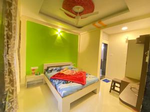 a bedroom with a bed with a green wall at Mayuri cottage in Mahabaleshwar