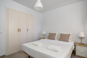 een witte slaapkamer met een groot bed met 2 handdoeken erop bij Fuengirola flat near the movida Ref 170 in Fuengirola