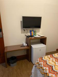 a room with a desk with a television and a bed at POUSADA ESTÂNCIA in Penedo