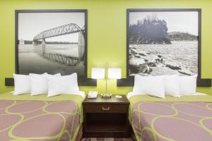 two beds in a room with two pictures on the wall at Super 8 by Wyndham Southaven in Southaven