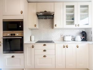uma cozinha branca com armários e electrodomésticos brancos em Pass the Keys Stylish 2 Bedroom Family Home em Worcester Park
