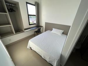 a bedroom with a white bed and a window at NANO Suítes in Uberlândia