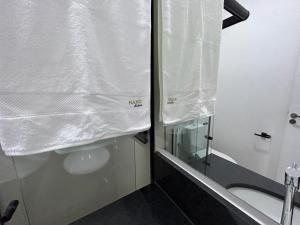 uma casa de banho com um chuveiro e um WC com um espelho. em NANO Suítes em Uberlândia