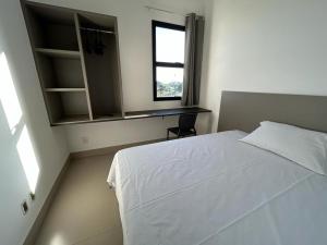 a bedroom with a white bed and a window at NANO Suítes in Uberlândia