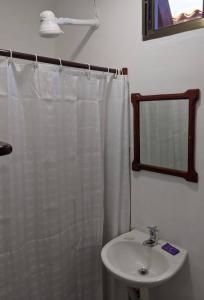 a bathroom with a white shower curtain and a sink at Chale's House Hotel in San Juan del Sur