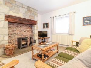 a living room with a stone fireplace and a couch at Canny Cottage in Morpeth