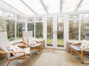 a conservatory with rocking chairs and windows at Canny Cottage in Morpeth
