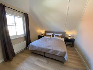 ein Schlafzimmer mit einem Bett und einem großen Fenster in der Unterkunft Villa Stilleven in Callantsoog