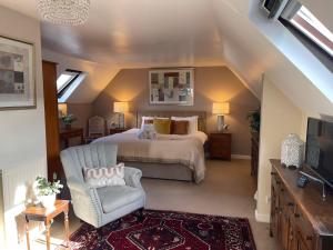 a bedroom with a bed and a chair and a television at Broadlands in Bourton on the Water