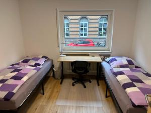 two beds in a room with a desk and a window at Beautiful, large and great apartment with balcony in top location in Karlsruhe